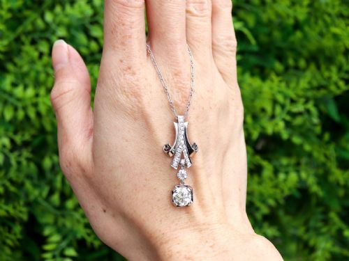 fig 1. An Art Deco platinum pendant set with brilliant-cut diamonds featuring a geometric ribbon motif suspended above a central diamond drop.