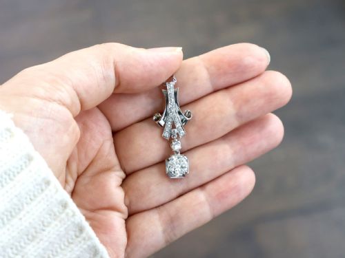 fig 2. An Art Deco platinum pendant set with brilliant-cut diamonds featuring a geometric ribbon motif suspended above a central diamond drop.