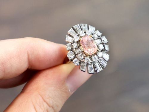 fig 2. A platinum cluster ring featuring a cushion-cut pink sapphire set in yellow gold claws surrounded by diamond halos.