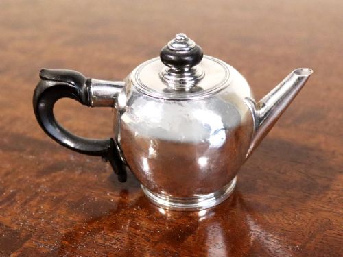 fig 1. A George II period silver miniature herb teapot with a tapered spout, moulded foot rim, and carved dark wooden handle and finial.