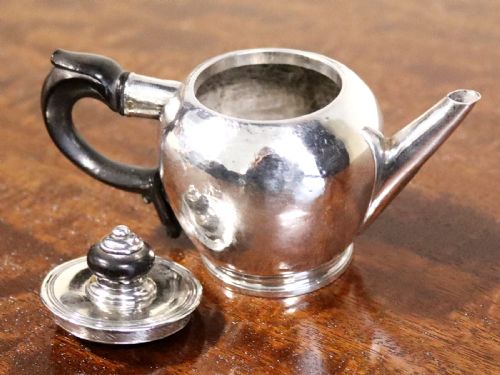 fig 2. A George II period silver miniature herb teapot with a tapered spout, moulded foot rim, and carved dark wooden handle and finial.