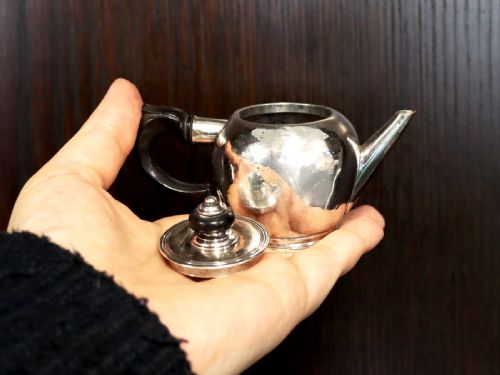 fig 3. A George II period silver miniature herb teapot with a tapered spout, moulded foot rim, and carved dark wooden handle and finial.
