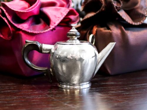 fig 4. A George II period silver miniature herb teapot with a tapered spout, moulded foot rim, and carved dark wooden handle and finial.