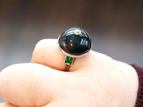 fig 1. An antique circular bloodstone cabochon ring featuring a central inset diamond, mounted in 14ct white gold with green gem-set shoulders.