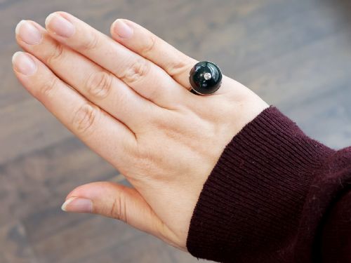 fig 2. An antique circular bloodstone cabochon ring featuring a central inset diamond, mounted in 14ct white gold with green gem-set shoulders.