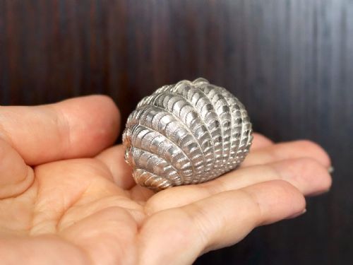 fig 2. An antique Victorian sterling silver nutmeg grater featuring a textured ribbed shell form with a hinged lid.