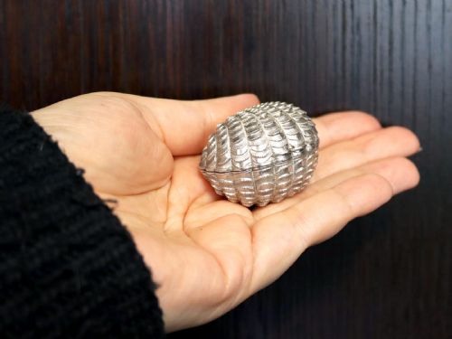 fig 3. An antique Victorian sterling silver nutmeg grater featuring a textured ribbed shell form with a hinged lid.