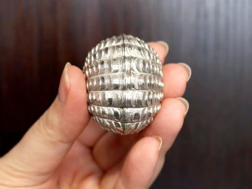 fig 4. An antique Victorian sterling silver nutmeg grater featuring a textured ribbed shell form with a hinged lid.