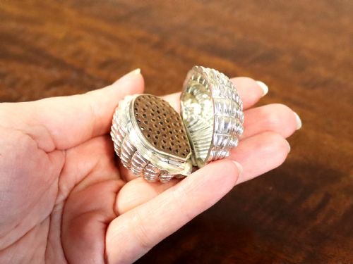 fig 5. An antique Victorian sterling silver nutmeg grater featuring a textured ribbed shell form with a hinged lid.