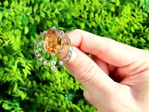 fig 1. A circular 14ct yellow gold openwork brooch featuring a central oval cut yellow topaz framed by diamond settings.