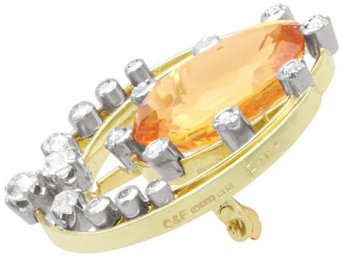 fig 5. A circular 14ct yellow gold openwork brooch featuring a central oval cut yellow topaz framed by diamond settings.