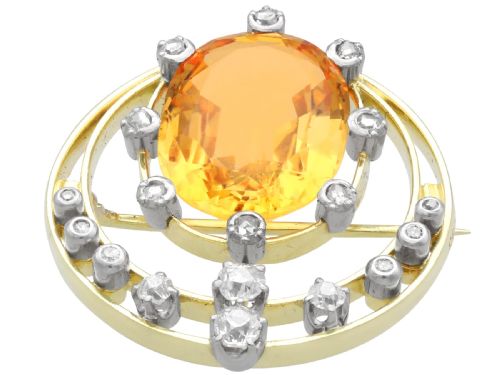 fig 6. A circular 14ct yellow gold openwork brooch featuring a central oval cut yellow topaz framed by diamond settings.