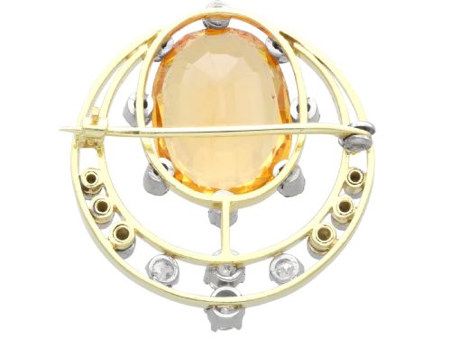 fig 7. A circular 14ct yellow gold openwork brooch featuring a central oval cut yellow topaz framed by diamond settings.