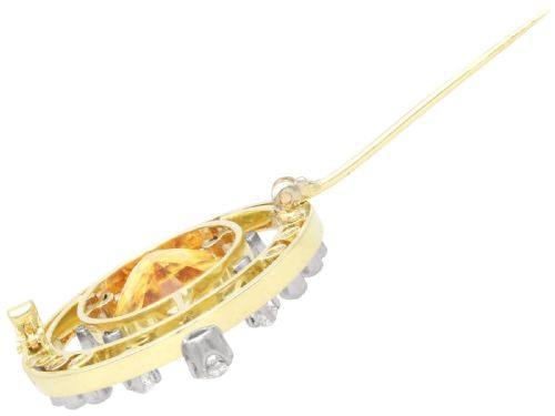 fig 8. A circular 14ct yellow gold openwork brooch featuring a central oval cut yellow topaz framed by diamond settings.