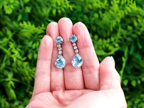fig 1. A pair of 14ct white gold drop earrings featuring round and pear-cut light blue aquamarines joined by a vertical line of small round diamonds.