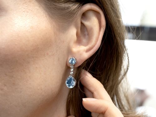 fig 3. A pair of 14ct white gold drop earrings featuring round and pear-cut light blue aquamarines joined by a vertical line of small round diamonds.