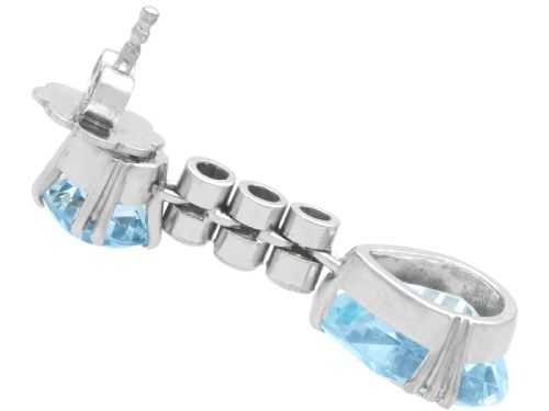 fig 5. A pair of 14ct white gold drop earrings featuring round and pear-cut light blue aquamarines joined by a vertical line of small round diamonds.