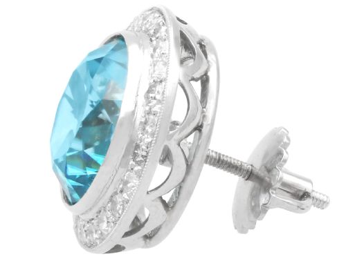 fig 5. A pair of 14ct white gold stud earrings featuring round blue zircon gemstones encircled by diamond halos with millegrain borders.