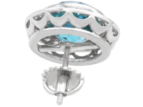 fig 6. A pair of 14ct white gold stud earrings featuring round blue zircon gemstones encircled by diamond halos with millegrain borders.