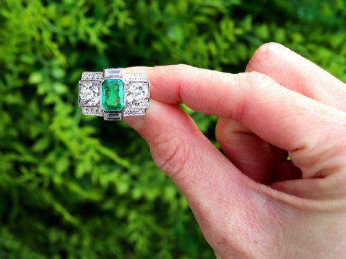 fig 1. An Art Deco platinum cocktail ring set with a central rectangular emerald flanked by round diamonds and baguette diamonds.