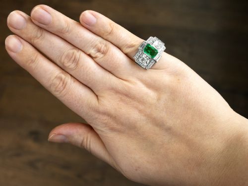 fig 4. An Art Deco platinum cocktail ring set with a central rectangular emerald flanked by round diamonds and baguette diamonds.