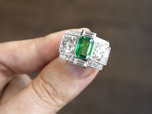 fig 5. An Art Deco platinum cocktail ring set with a central rectangular emerald flanked by round diamonds and baguette diamonds.
