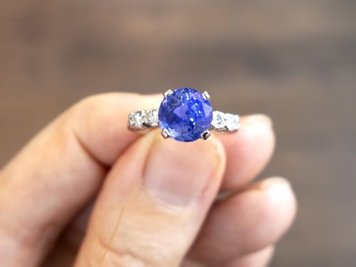 fig 3. A round blue sapphire set in a platinum band flanked by round diamonds on each side.