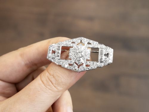 fig 2. An Art Deco platinum plaque brooch featuring an intricate geometric openwork setting encrusted with round and baguette cut diamonds.