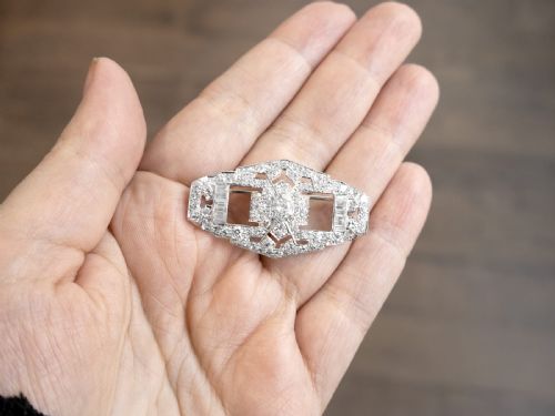 fig 3. An Art Deco platinum plaque brooch featuring an intricate geometric openwork setting encrusted with round and baguette cut diamonds.