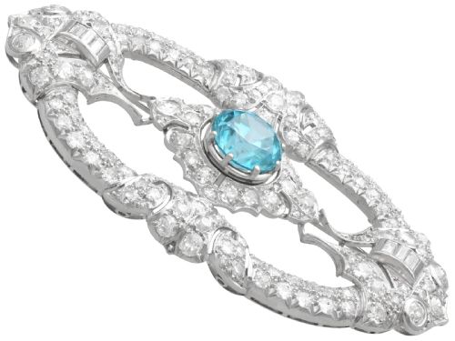fig 7. An oval Art Deco platinum brooch featuring an openwork geometric frame set with diamonds and a central round brilliant blue zircon.