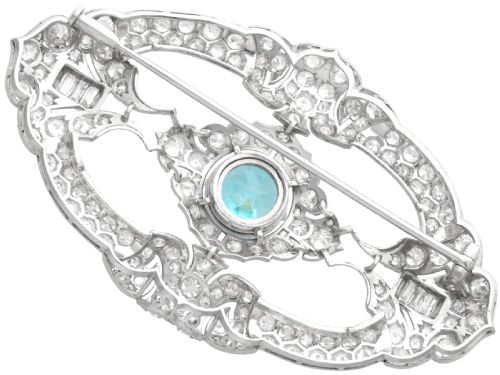 fig 8. An oval Art Deco platinum brooch featuring an openwork geometric frame set with diamonds and a central round brilliant blue zircon.