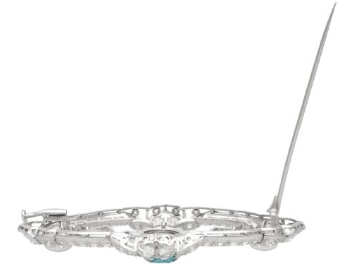 fig 9. An oval Art Deco platinum brooch featuring an openwork geometric frame set with diamonds and a central round brilliant blue zircon.