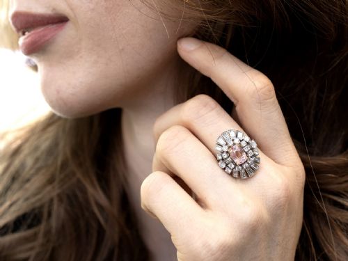 fig 3. A platinum cluster ring featuring a cushion-cut pink sapphire set in yellow gold claws surrounded by diamond halos.