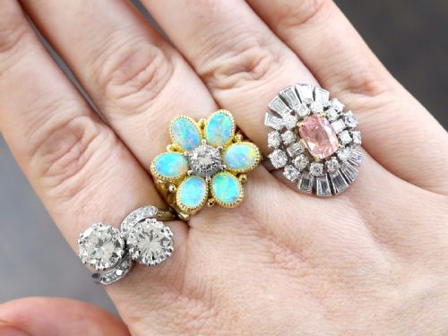 fig 5. A platinum cluster ring featuring a cushion-cut pink sapphire set in yellow gold claws surrounded by diamond halos.