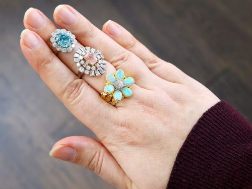 fig 6. A platinum cluster ring featuring a cushion-cut pink sapphire set in yellow gold claws surrounded by diamond halos.