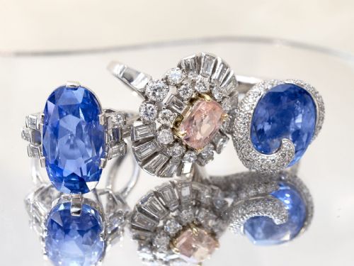 fig 8. A platinum cluster ring featuring a cushion-cut pink sapphire set in yellow gold claws surrounded by diamond halos.