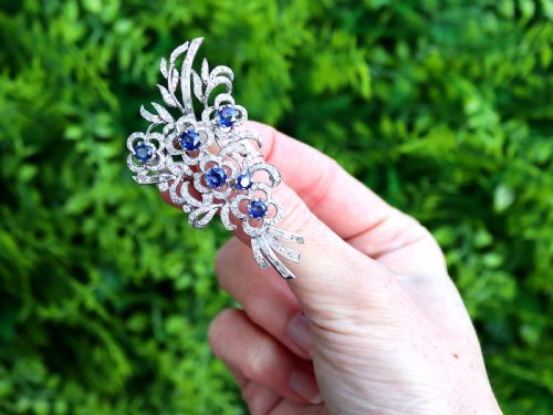 fig 1. An Art Deco platinum brooch styled as a floral spray, set with round blue sapphires and accented with pave and baguette-cut diamonds.