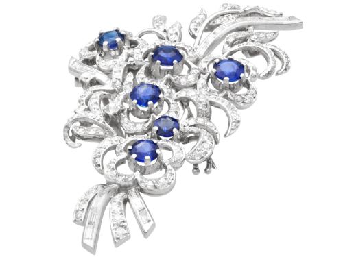 fig 5. An Art Deco platinum brooch styled as a floral spray, set with round blue sapphires and accented with pave and baguette-cut diamonds.
