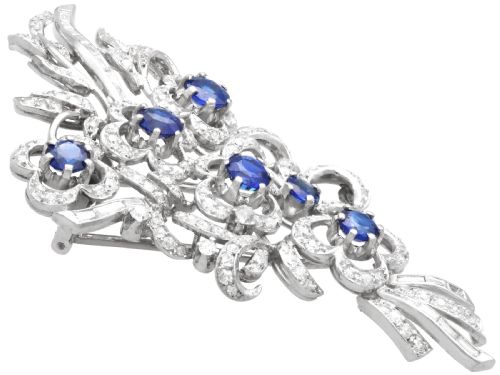 fig 6. An Art Deco platinum brooch styled as a floral spray, set with round blue sapphires and accented with pave and baguette-cut diamonds.