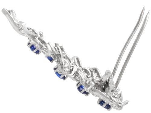 fig 7. An Art Deco platinum brooch styled as a floral spray, set with round blue sapphires and accented with pave and baguette-cut diamonds.