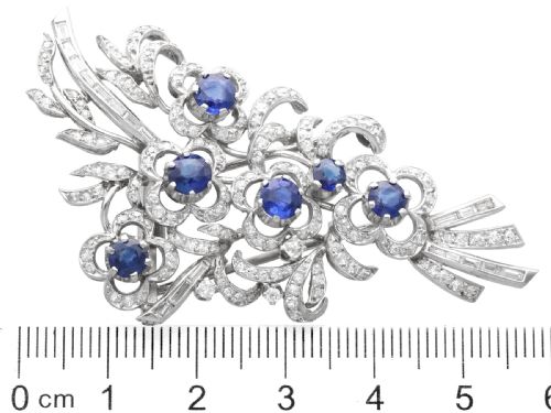 fig 9. An Art Deco platinum brooch styled as a floral spray, set with round blue sapphires and accented with pave and baguette-cut diamonds.