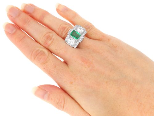 fig 12. An Art Deco platinum cocktail ring set with a central rectangular emerald flanked by round diamonds and baguette diamonds.