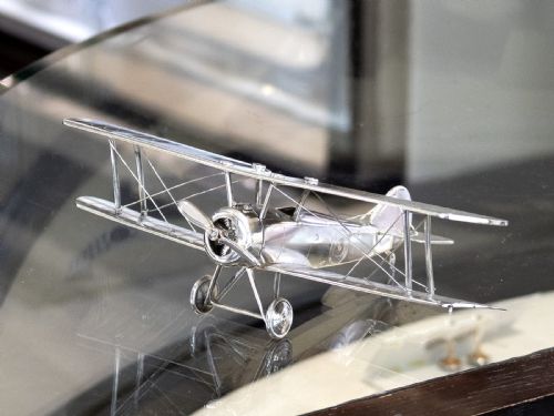 fig 5. A sterling silver scale model of a George V era Sopwith biplane featuring twin wings, a propeller, two wheels, and wire rigging.