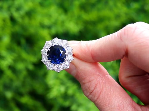 fig 1. A round deep blue sapphire framed by a halo of ten round brilliant diamonds on an 18ct yellow gold band.
