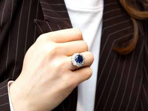 fig 3. A round deep blue sapphire framed by a halo of ten round brilliant diamonds on an 18ct yellow gold band.