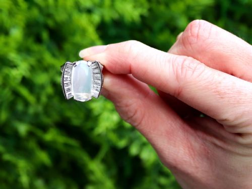 fig 1. An Art Deco platinum dress ring featuring a central oval cabochon moonstone flanked by stepped baguette-cut diamonds.
