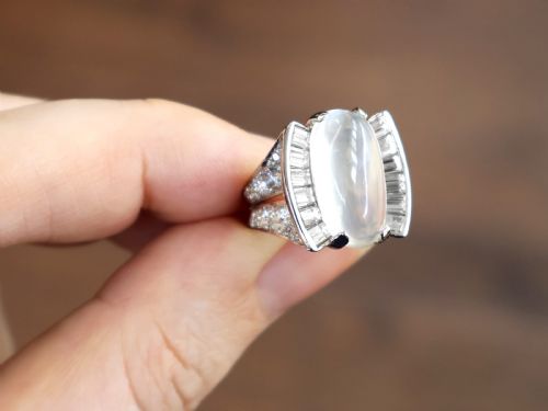 fig 7. An Art Deco platinum dress ring featuring a central oval cabochon moonstone flanked by stepped baguette-cut diamonds.