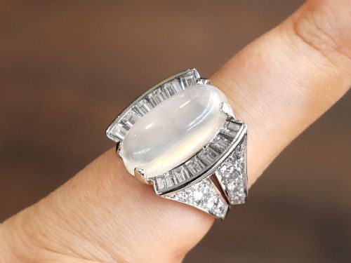fig 8. An Art Deco platinum dress ring featuring a central oval cabochon moonstone flanked by stepped baguette-cut diamonds.