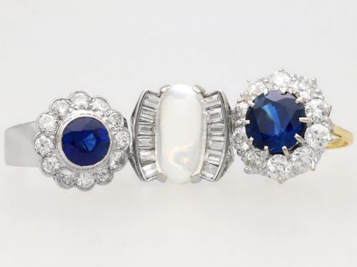 fig 7. A vintage 18ct white gold cluster ring set with a central round blue sapphire surrounded by a halo of brilliant diamonds with a scalloped edge.