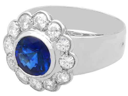 fig 8. A vintage 18ct white gold cluster ring set with a central round blue sapphire surrounded by a halo of brilliant diamonds with a scalloped edge.